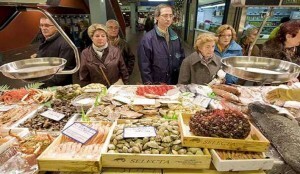 Varias personas hacen cola para comprar en un mercado/20minutos