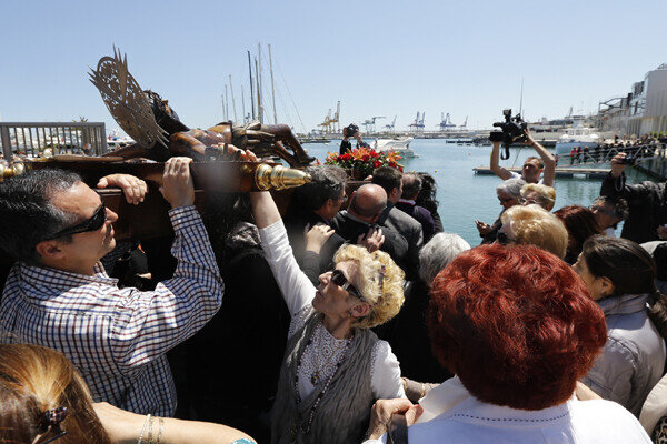 Una mujer toca la figura del crucificado a hombros de los devotos/m.molines