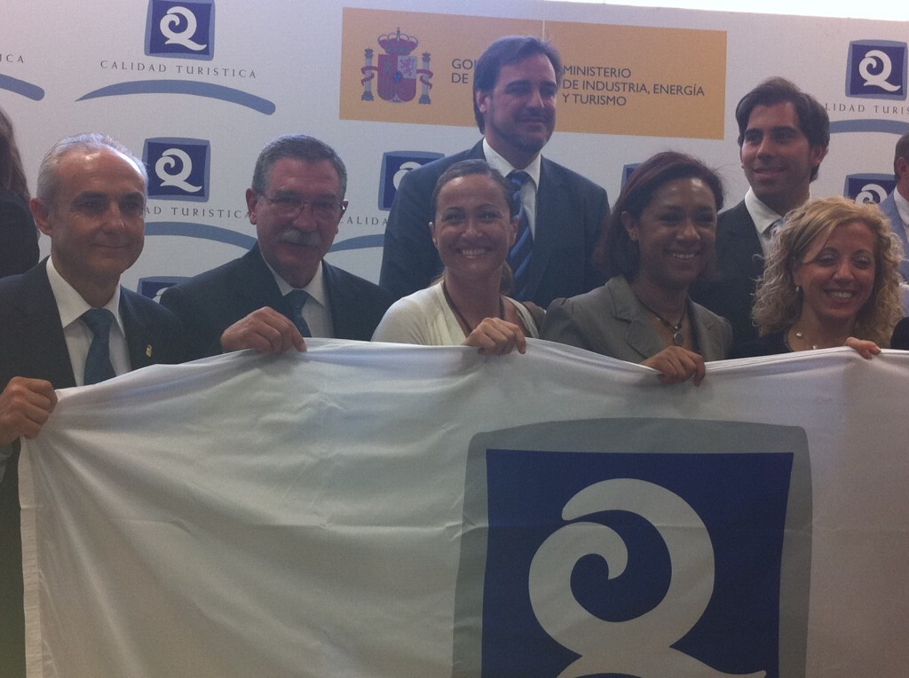 La concejal de Playas sostiene la bandera de Q de calidad con otros ediles