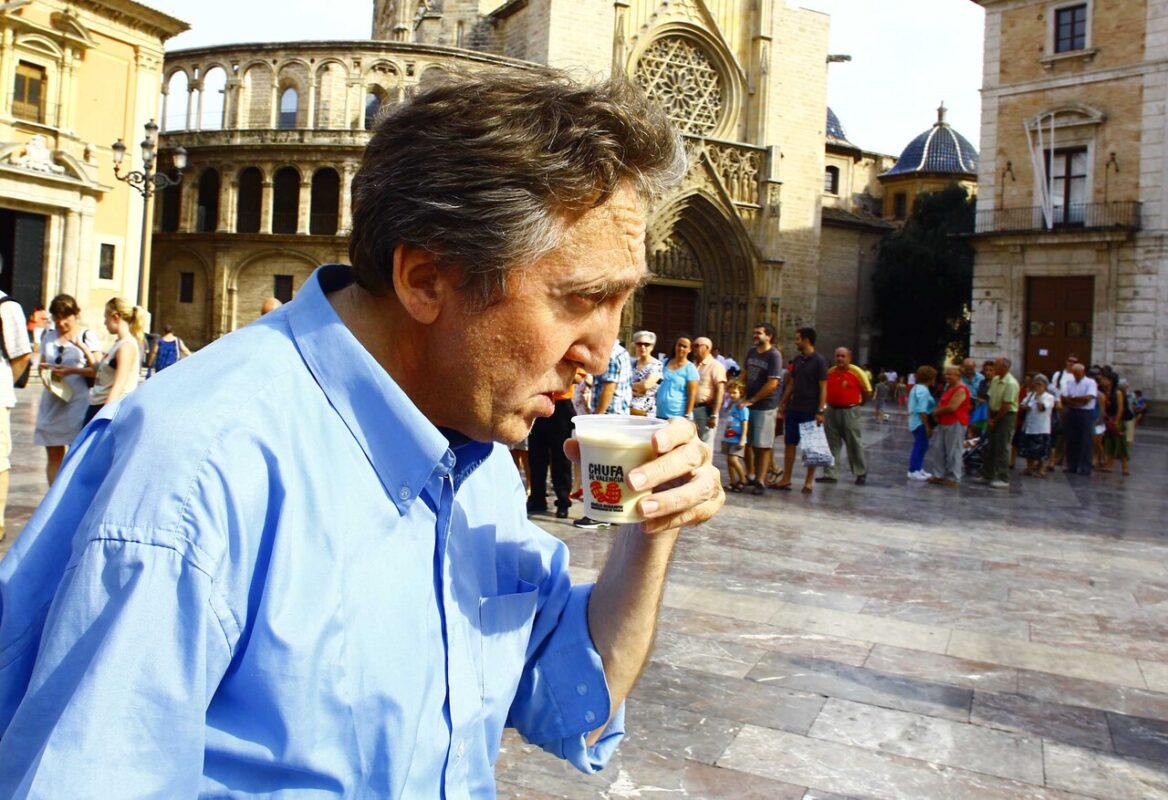 Un hombre toma un vaso de horchata en la plaza de la Virgen
