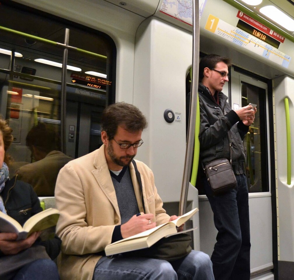 Un usuario del metro lee mientras realiza el desplazamiento/gva