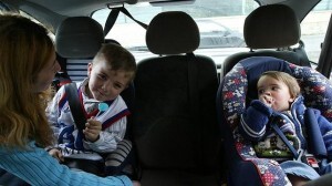 Dos niños en sendas sillas en el asiento trasero de un vehículo