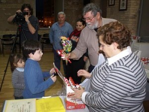 La presidenta de la junta mayor entrega un detalle a un niño/eos