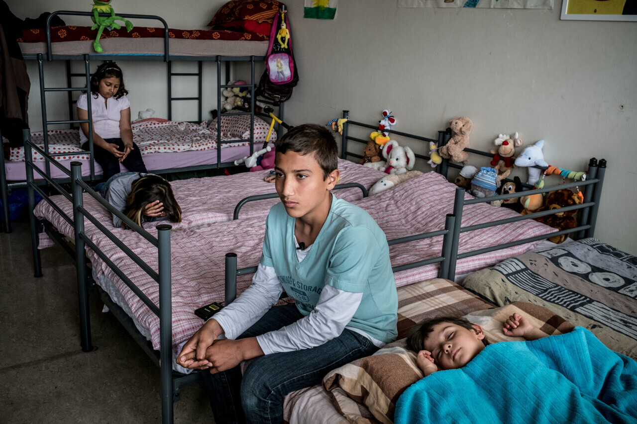 Syrian Kurds Shanya Omar, 2 1/2, daughter Mahi Omar (grey sweater with print), 8, daughter Ajin Omar (light pink shirt), 12, and brother Chimen Omar (teal t-shirt), 12, at the Karlshorst emergency housing estate, a refugee camp administered by the German Red Cross, in Karlshorst, a middle class suburb of Berlin, Germany on May 26, 2016. The camp buildings were originally Russian military barracks prior to the fall of the Iron Curtain, and today they house 1,000 refugees (350 of whom are children), including 500 people from Syria, 200 from Afghanistan, 100 from Iraq, and another 200 from Eastern and South Asia and parts of Africa. When the camp opened in August, 2015, it was filled to the capacity of 1,000 people within a week. The family heard fighting close to their house in Qamishli, Syria on December 26, 2015, and immediately packed their bags to leave for Germany. When their son, Chimen got home from school that day, they fled, making the journey non-stop to Europe in five days. When they arrived in Berlin, a friend told Mohammad to apply for Asylum in Hamburg where he said paper work was being processed faster. Upon traveling there, Mohammad and his family were reassigned to Berlin, where they live today. Since January 2015, more than 1,200,000 people crossed the Mediterranean. Yet, the refugee and migrant crisis has entered a new phase since the border closures in the Balkans and the EU-Turkey agreement in March. The number of people mostly from Syria, Afghanistan and Iraq crossing the Mediterranean from Turkey to Greece has dropped dramatically. At the same time, vast numbers of refugees and migrants (largely from sub-Saharan Africa) are using the much more dangerous Central Mediterranean crossing from North Africa to Italy. As a result, only during the past two weeks, nearly 1,000 people lost their lives- one third of all deaths in the Mediterranean since the beginning of the year. The number of children among them is unknown as there is only pa