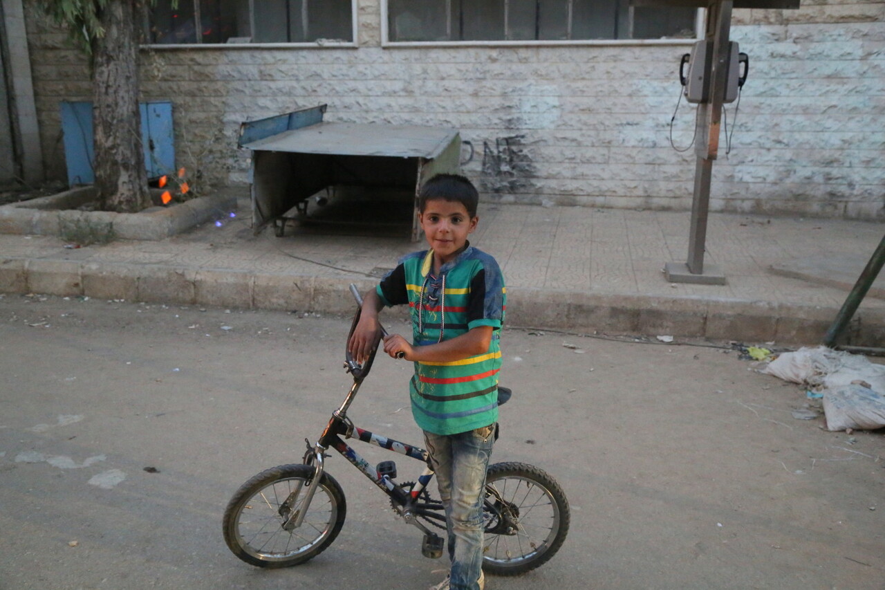 On 25 September 2016, a boy stands with his bicycle in Madaya in the Syrian Arab Republic. UNICEF participated in UN-interagency convoys to four towns, delivering urgently needed humanitarian assistance to 60,000 people. Under the so-called Four Town Agreement, convoys delivered supplies to people in Madaya and Zabadani in Rural Damascus and Foah and Kefraya in Idlib governorate. UNICEF delivered health, nutritional supplements, hygiene supplies, educational supplies and childrenÕs clothes for 20,000 people in Madaya and Zabadani Ð and the same supplies for 10,000 people in Foah and Kafraya. In Madaya, UNICEF screened children for malnutrition and supported local health teams. The convoys were the first time UNICEF and our partners have been able to access the four towns since late April.