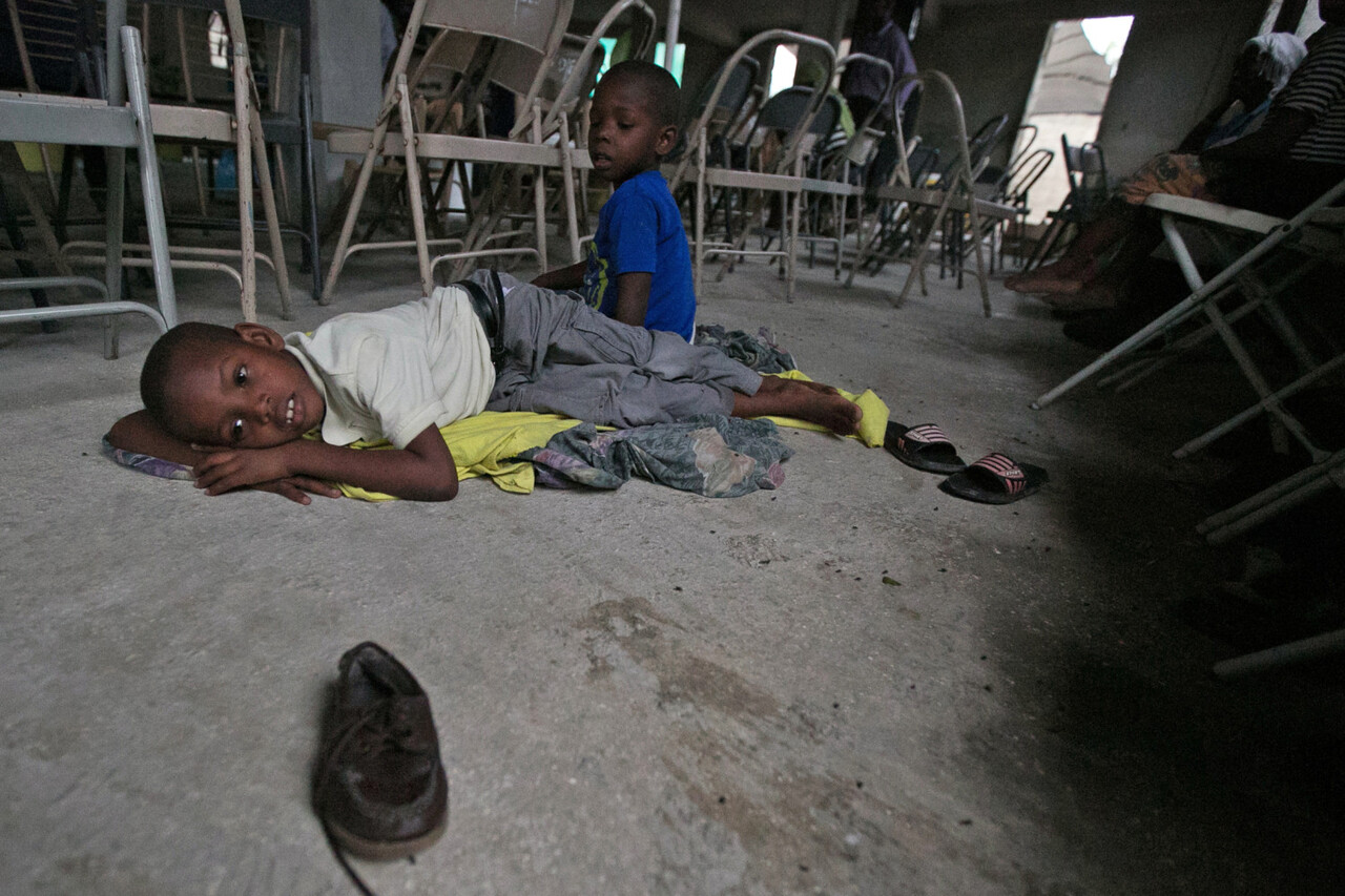 On 3 October 2016, a boy and his brother rest in a church in Croix des Bouquets, a neighbourhood on the east of Port-au-Prince where they are staying to find some protection from hurricane Matthew. The hurricane is expected to hit the neighbourhood where they live, Cite Soleil, which is a populated slum area right by the ocean in Port-au-Prince with houses made out of shacks and canals filled with garbage. On 4 October 2016, more than 4 million children may be exposed to the damage of Hurricane Matthew, UNICEF said as the Category 4 storm made landfall on the impoverished Caribbean island. Strong winds and torrential rains are battering the island, raising the risk of floods and landslides. The airport remains closed and children have been told to stay home from school particularly as many schools are being used to shelter evacuees. Haiti is still recovering from the 2010 earthquake, with 55,000 people still living in shelters. The southern coast, where the storm is expected to hit the most, is one of the poorest and most densely populated parts of the country. In a country where less than 1 in 5 people in rural areas have access to improved sanitation and 40 per cent of people use unsafe water sources, it is feared that the hurricane will worsen an already precarious situation. Cholera is endemic and with more than 27,000 suspected cholera cases reported already this year an estimated one third of them children any damage to water and sanitation infrastructure or largescale displacement could put children and families at greater risk of infection. UNICEF is working to support the Governments humanitarian response. Life-saving supplies for 10,000 people are in place and ready to be distributed to the most affected families in the worst hit areas. They include water bladders and chlorination tablets, hygiene kits and mosquito nets.
