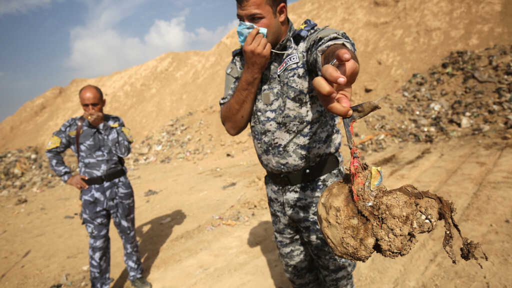 EDITORS NOTE: Graphic content / A member of the Iraqi forces holds a skull they dug up from a mass grave they discovered in the Hamam al-Alil area on November 7, 2016 after they recaptured the area from Islamic State (IS) group jihadists during the ongoing operation to retake Mosul, the last IS-held Iraqi city. Iraqi investigators carried out an initial examination of a mass grave site discovered in an area south of Mosul that was recently retaken from the Islamic State group.  / AFP PHOTO / AHMAD AL-RUBAYE